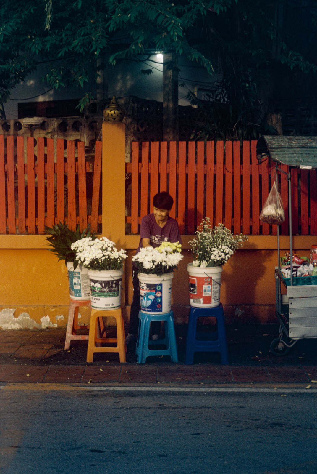 A flower stall in front of an orange fence